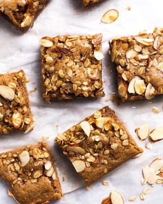 several pieces of dessert sitting on top of a piece of parchment paper with almonds