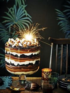 a birthday cake with lit candles on top and other decorations around the edges, sitting on a table in front of a palm tree