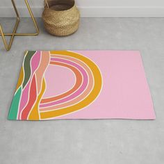 a pink rug with multicolored circles on it next to a basket and chair