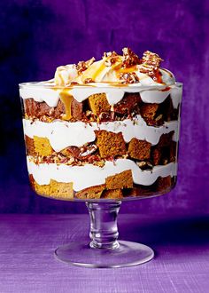 a cake with white frosting and nuts on top is sitting in a glass dish