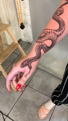 a woman's arm with a snake tattoo on it