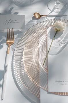 a table setting with place cards, silverware and a single rose on the plate