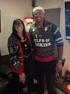 a man and woman standing next to each other in front of a christmas tree wearing ugly sweaters