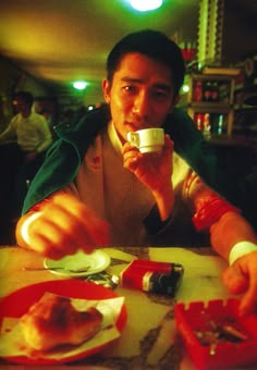 a man sitting at a table drinking from a cup