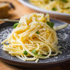 a black plate topped with spaghetti and parmesan cheese