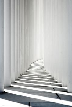 white columns are lined up in the middle of an empty room with light coming through them