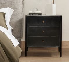 a night stand with two drawers next to a bed