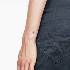 a person with a small tattoo on their left arm, wearing dark blue jeans and a black t - shirt