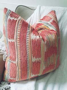 a red pillow sitting on top of a white bed