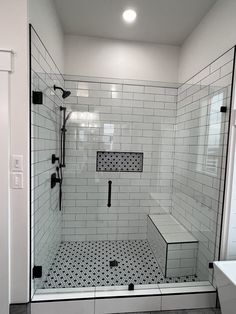 a walk in shower with black and white tile