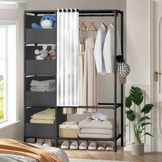 an open closet with clothes, shoes and other items hanging on the wall next to a bed