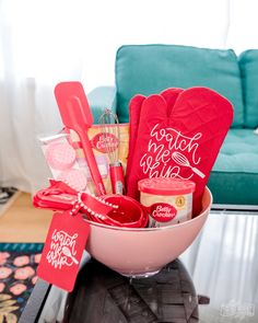 a pink bowl filled with red items on top of a table next to a blue couch