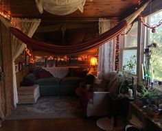 a living room filled with furniture and lots of lights hanging from the ceiling next to windows