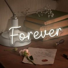 there is a light up sign that says forever on the table next to some books