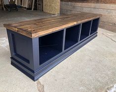 a wooden table with blue glass doors on the top and bottom shelf, in front of some wood planks