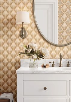 a bathroom vanity with a mirror, sink and flowers on it in front of a gold wallpaper