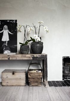 two vases with white flowers are sitting on a table next to an old trunk