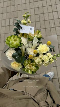 a bouquet of flowers sitting on top of a table next to a person's legs