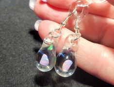 Make a splash with these Mermaid's Tears earrings!  These gorgeous hand-blown teardrop earrings are made with only the highest quality borosilicate glass and features a mesmerizing Gilson opal polished nugget that shimmers with blue, green, yellow, and even a hint of red within the opal encased in glass. These opals flash different colors when angled in different directions and are pictured with sterling silver fishhooks. These blown glass opal earrings come mounted on sturdy sterling silver fis Clear Glass Drop Jewelry, Clear Drop-shaped Glass Jewelry, Unique Teardrop Hypoallergenic Jewelry, Iridescent Drop Earrings For Gift, Unique Hypoallergenic Teardrop Jewelry, Clear Teardrop Jewelry With Matching Earrings, Hypoallergenic Glass Teardrop Jewelry, Iridescent Teardrop Earrings For Gift, Opal Teardrop Earrings As Gift