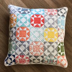 a colorful quilted pillow sitting on top of a wooden floor