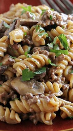 a close up of a plate of food with pasta and meat on it next to a fork