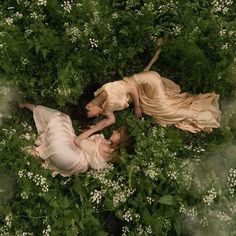 two women are laying in the grass together