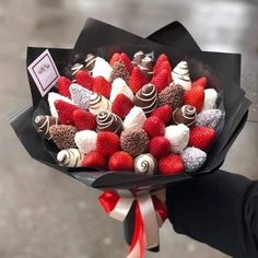 a bouquet of strawberries and chocolates wrapped in black paper