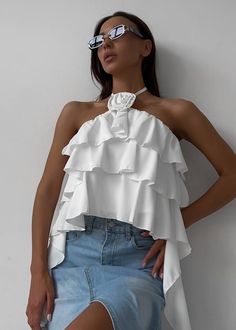 This luxurious Halter 3D Flower Detail Ruffled Crop Top will add unique sophistication to any wardrobe. Crafted with delicate ruffles and detailed with floral, this halter-style peplum top exudes opulence and elegance. Enjoy the perfect combination of charm and comfort. Fabric: Polyester Chic Party Tops With Ruffle Hem, Feminine Party Tops With Ruffles, Chic Tops With Ruffle Hem For Party, Glamorous Summer Ruffle Blouse, Glamorous Spring Blouse With Ruffles, Spring Party Chiffon Tops, Chic Ruffled Halter Top For Spring, Glamorous Halter Neck Top For Spring, Summer Party Blouse With Ruffle Hem