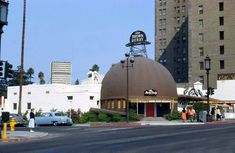 people are standing in front of a building with a large dome on the roof that has a sign above it