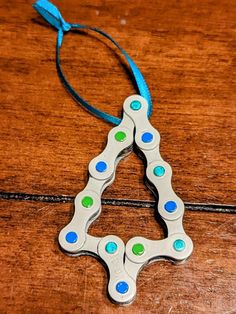 an ornament shaped like a christmas tree on a wooden table with blue and green beads