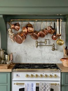 an oven with pots and pans hanging on the wall