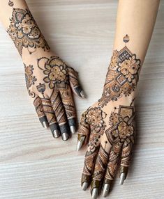 two hands with henna tattoos on them