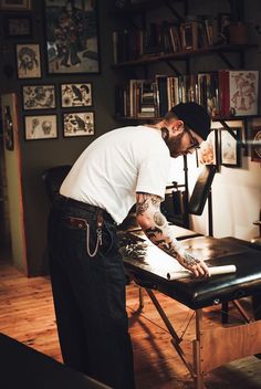 a man with tattoos on his arm standing over a table