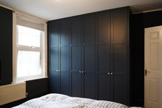 a bedroom with black cabinets and a white blanket on the bed in front of it