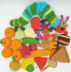 crocheted toys are laid out on a white surface, including fruits and vegetables