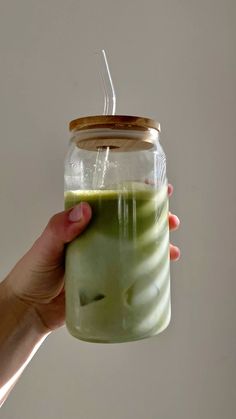 a hand holding a mason jar filled with green liquid