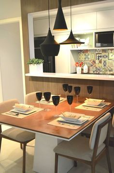 a dining room table with place settings and wine glasses on it in front of the counter