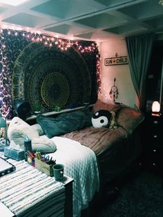 a room with a bed, desk and wall hanging in the corner that has lights on it