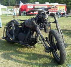 an old motorcycle is parked in the grass with people standing around and looking at it