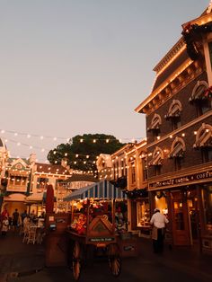 an outdoor shopping area with lights strung over the buildings