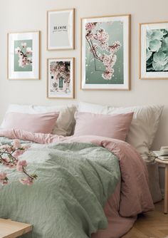 a bed with pink and green comforter in a bedroom next to pictures on the wall