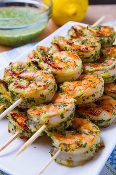 shrimp skewers with pesto sauce on a white plate