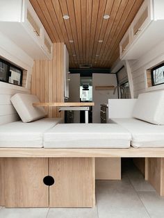 the inside of a camper with white couches and wood paneling on the ceiling