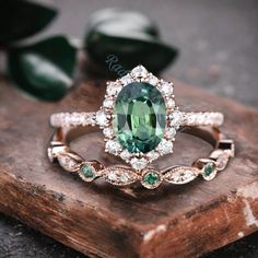 an oval green gemstone surrounded by white diamonds on top of a wooden surface with leaves