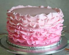 a cake with pink icing and ruffles on top