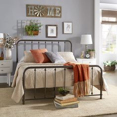 a bedroom with a metal bed frame and orange throw pillows on top of the bed