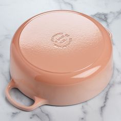 a pink casserole sitting on top of a marble counter