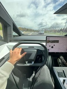 a man driving a truck on the road with his hand on the steering wheel while using a laptop