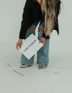 a woman in ripped jeans holding a sign