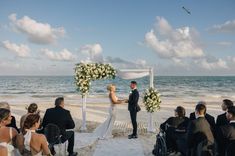 a bride and groom standing at the end of their wedding ceremony on the beach with an ocean in the background